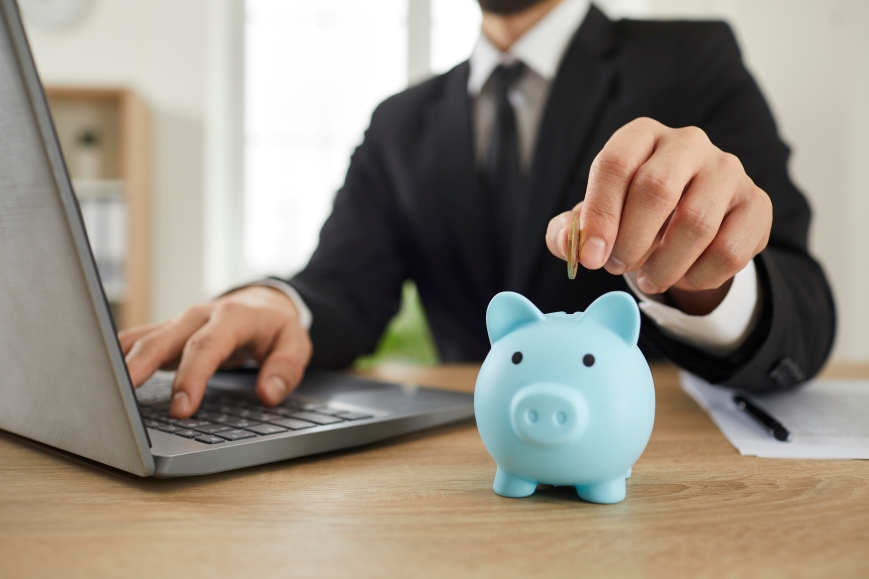 Man at desk saving money in piggy bank