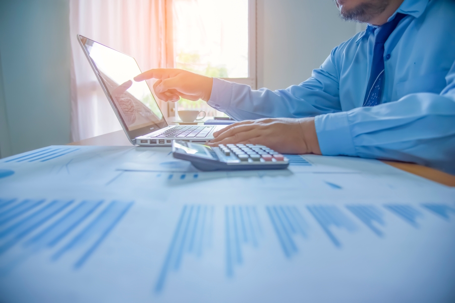 Advisor at desk with computer and charts, assessing tax-loss harvesting opportunities