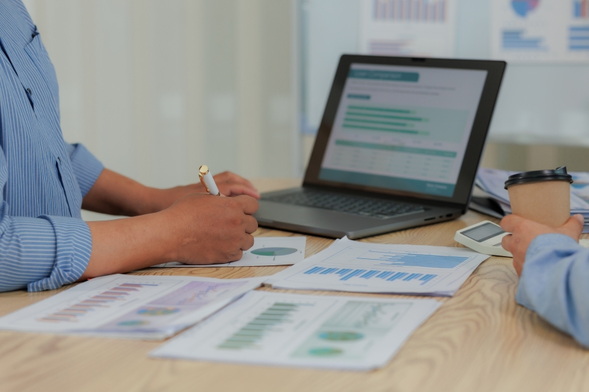 Two people at a table reviewing investment charts and graphs