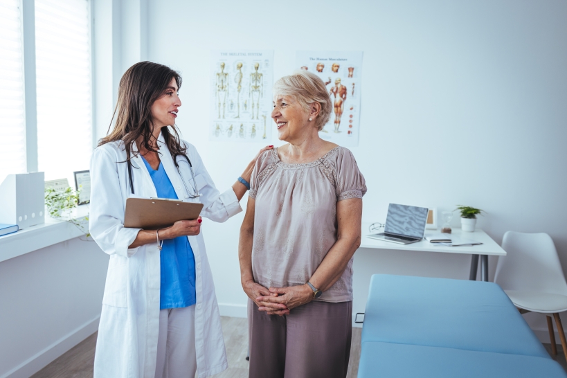 Older woman standing in doctor's office talking to medical provider